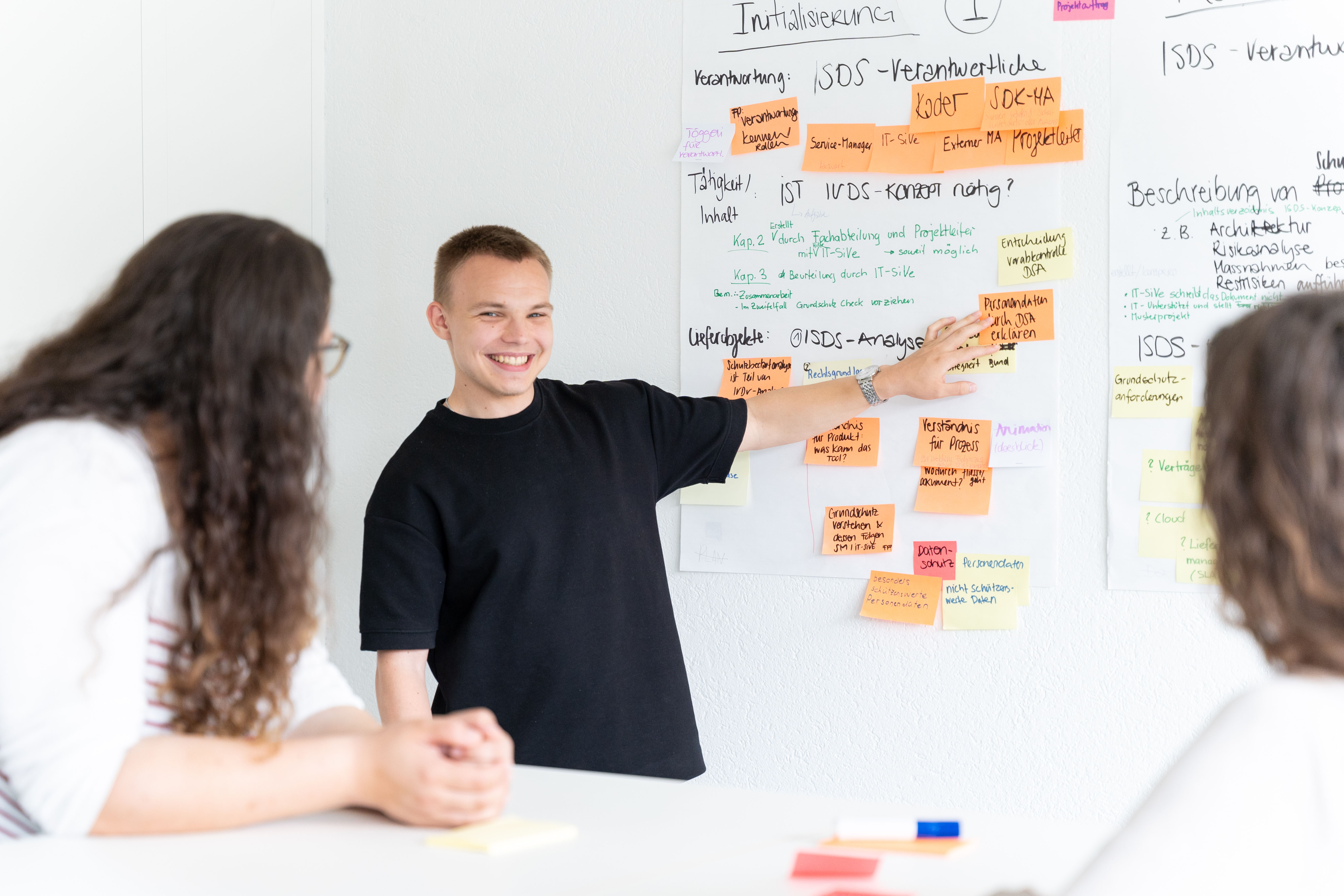 Lernender hält vor anderen Mitarbeitenden eine Präsentation.